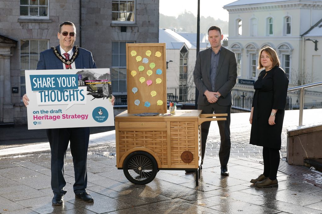 Photo of Lord Mayor holding billboard which has 'Share your thoughts' written on it. Behind the Lord Mayor is two figures - Head of Tourism and Representative from the Heritage Fund.